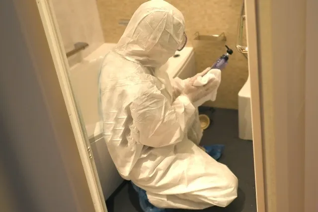 防護服を着ながらお風呂の中でボトルの清掃をしている様子