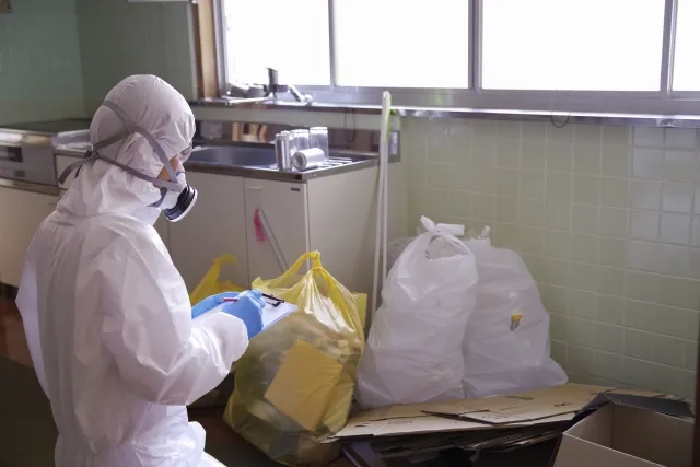 防護服を着ながらバインダーに挟んだ紙に書き込みしている