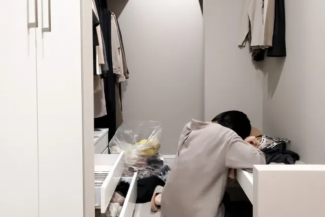 クローゼットで洋服の片付けをしている女性の後ろ姿