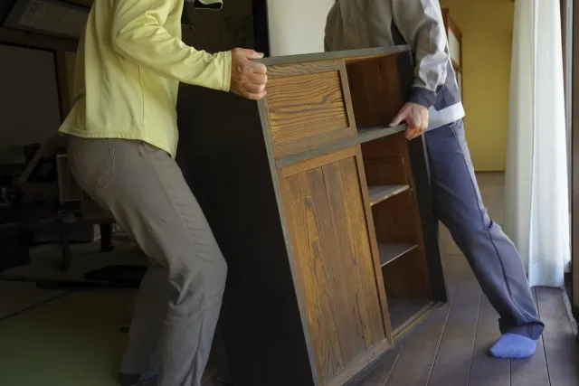 生前整理で木製の棚を運ぼうとしている老夫婦