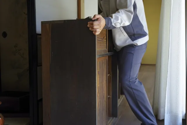 生前整理で木製の棚を動かそうとしている男性