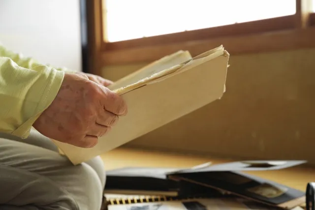 遺品のノートを見ている年配女性の手