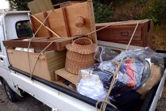 不用品をいっぱい荷台に載せた白い軽トラック
