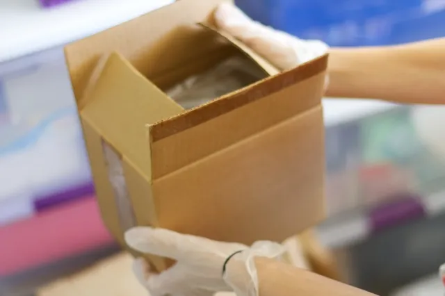遺品整理で小さいダンボールをビニール手袋をして運んでいる手