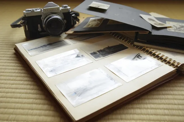畳の上に置かれている白黒の写真がはさまったアルバムと、カメラ