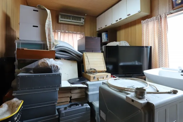 遺品でテレビや乾燥機など不用品でいっぱいになっている部屋