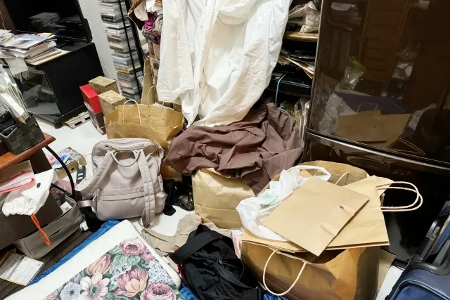 部屋の中で、カバンや紙袋、シーツなど色々なもので散らかっている様子