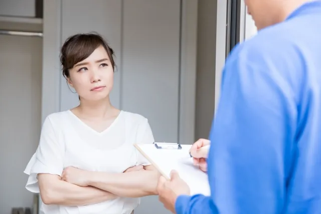 見知らぬ青い作業着を着た業者が来て、腕を組んで不機嫌そうな顔をしている女性
