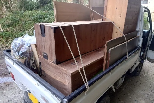 木製のタンスなどの不用品を荷台いっぱいに載せている軽トラック