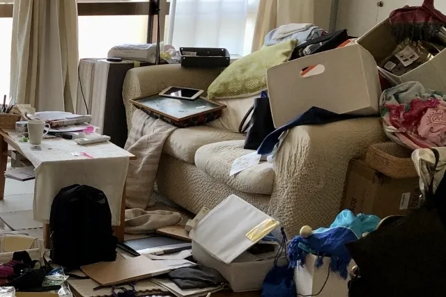 小物入れやカバン、ファイルなど色々な物が部屋のソファやテーブルなどに散乱して汚れている