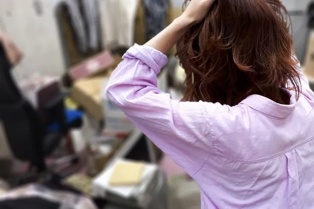 ゴミ屋敷となった部屋を掃除しようとして頭を抱える女性の後ろ姿