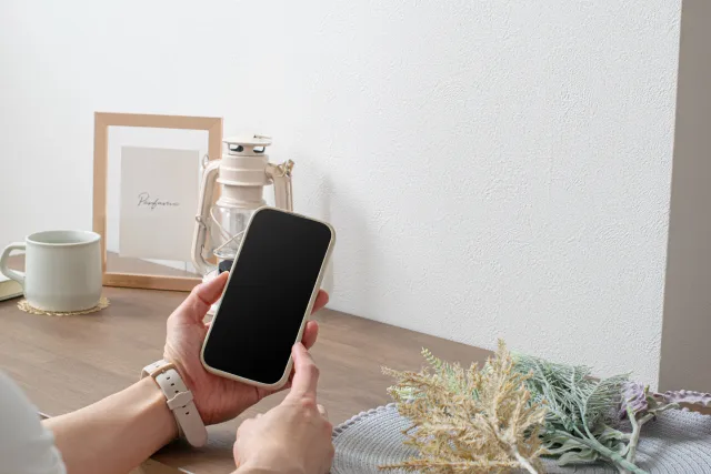 スマホを操作する左手に時計をしている女性の手