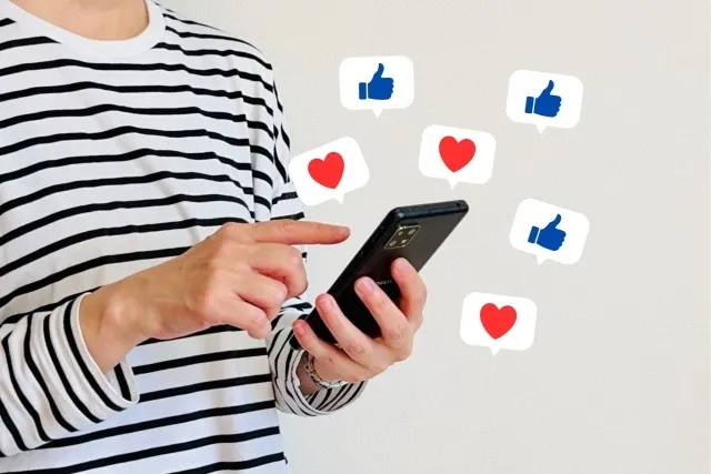 ボーダー長Tを着た男性がスマホを操作していいねなどのレビューを見ているイメージ画像