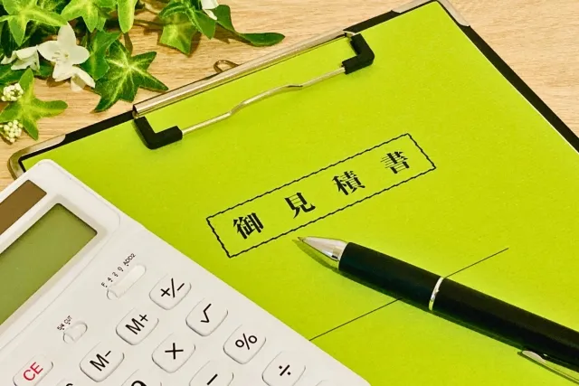 バインダーに挟まれている見積書の上にボールペンと電卓が置かれている